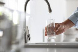 Man,Pouring,Water,Into,Glass,In,Kitchen,,Closeup